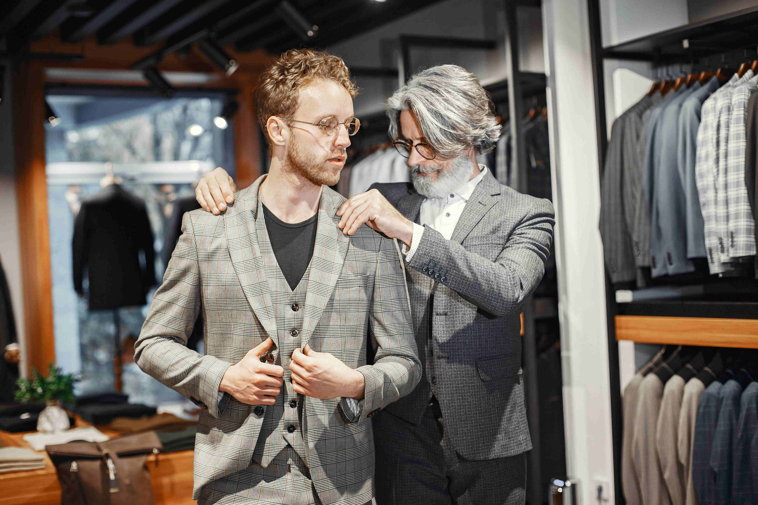 Expert tailor adjusting a custom-fitted plaid suit on a client inside a luxury boutique, representing Bold Italia Suit's premium tailoring process and craftsmanship.