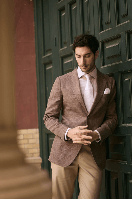 Mens brown textured blazer with white shirt and tie paired with beige tailored dress pants