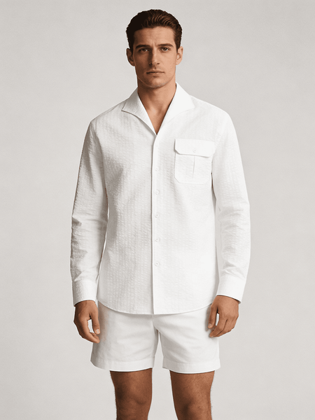 Man wearing a white linen shirt and shorts on a plain background