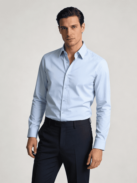 Man wearing a light blue dress shirt and dark pants on a plain background