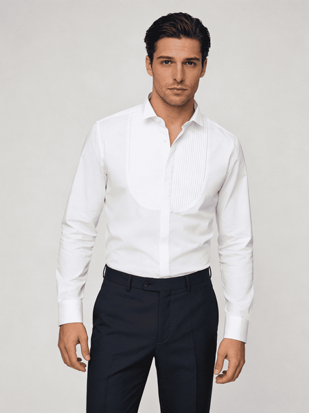 Man wearing a white dress shirt and dark pants against a plain background