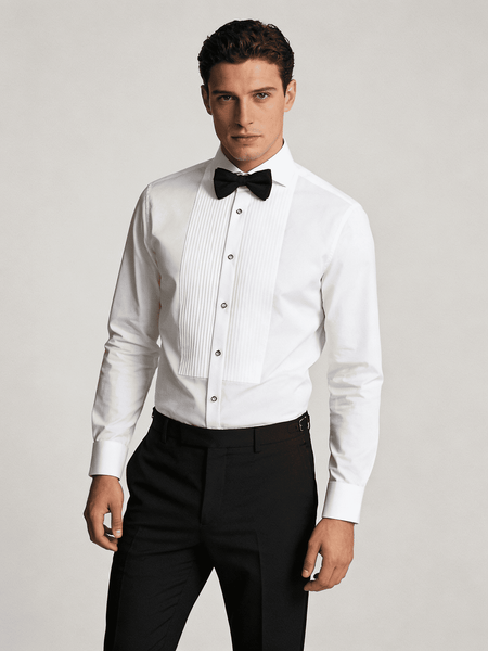 Man wearing a white dress shirt with black bow tie and black pants on a light gray background