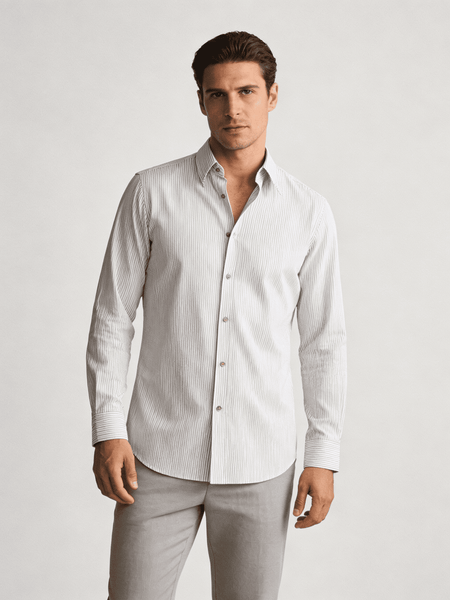 Man wearing a light-colored dress shirt and pants on a plain background