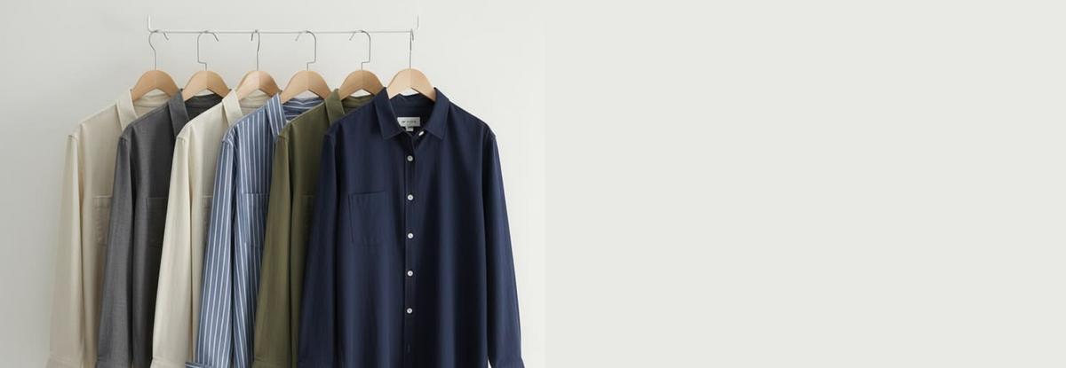 Men's custom dress shirts in navy, olive, blue stripe, gray, and neutral colors displayed on wooden hangers.