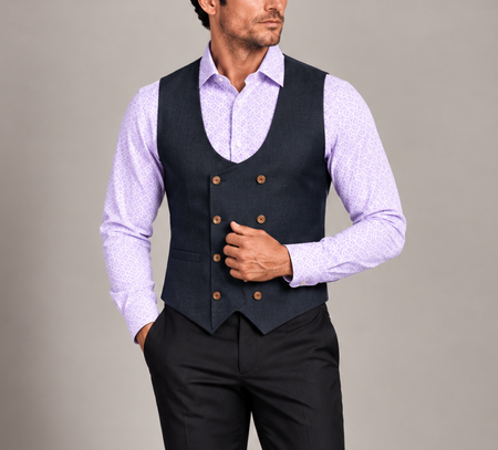 Man wearing a navy double-breasted vest with a lavender patterned dress shirt and black trousers.
