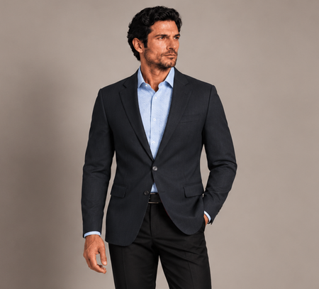 Man wearing a tailored navy blazer with a light blue dress shirt and black trousers for a polished business look.
