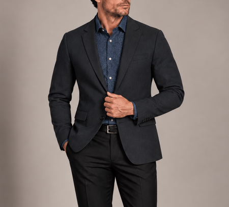 Man wearing a tailored charcoal blazer with a navy patterned dress shirt and black trousers for a refined smart-casual look.