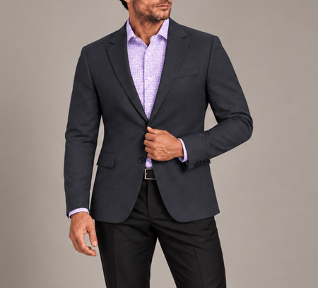 Man wearing a tailored navy blazer with a lavender patterned dress shirt and black trousers.